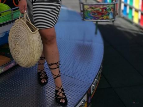 look verano con body amarillo con volantes de primark con falda de rayas y capazo redondo de mimbre y sandalias negras en un carrusel