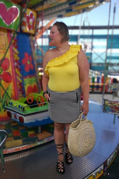 look verano con body amarillo con volantes de primark con falda de rayas y capazo redondo de mimbre y sandalias negras en un carrusel