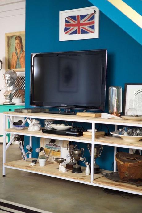 estantería de metal y madera para la tv, pared pintada en azul