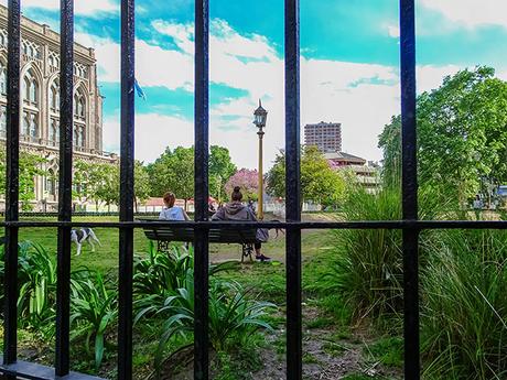 gente de espaldas en plaza vistas detrás de una reja.