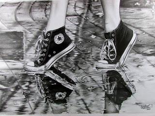 Fotografía en blanco y negro de las piernas de una chica joven a la que solo se le ven las zapatillas tipo Converse negras y blancas, caminando bajo la lluvia.