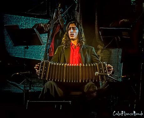 Un bandoneonista tocando un tango en escenario.