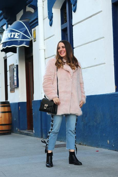 Con abrigo rosa y jeans entre lazados