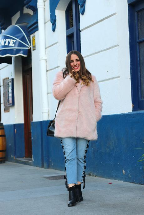 Con abrigo rosa y jeans entre lazados