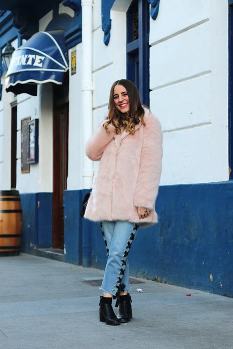 Con abrigo rosa y jeans entre lazados