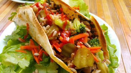 Tacos rellenos de judías, arroz y verduras con salsa de aguacate y cilantro