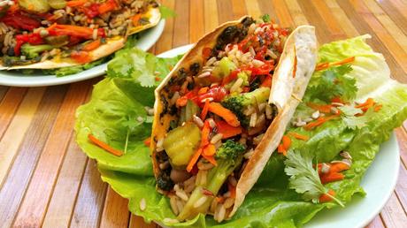Tacos rellenos de judías, arroz y verduras con salsa de aguacate y cilantro