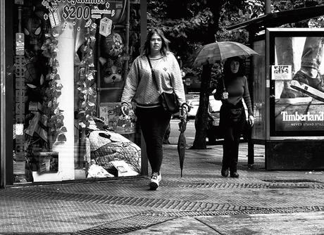 Dos mujeres caminando una con paraguas abierto.