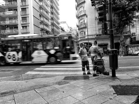 Dos empleados barrenderos charlando en una esquina.