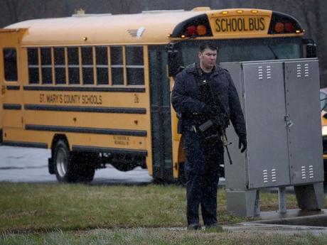 FOTO: Un agente de la ley fuertemente armado monta guardia mientras los estudiantes de Great Mills High School son evacuados a Leonardtown High School después de un tiroteo en la escuela en la High School secundaria de Great Mills, el 20 de marzo de 2018.