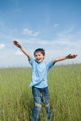 Un niño extiende los brazos sonriendo sobre un campo de trigo y el cielo azul Comprada en De Istock