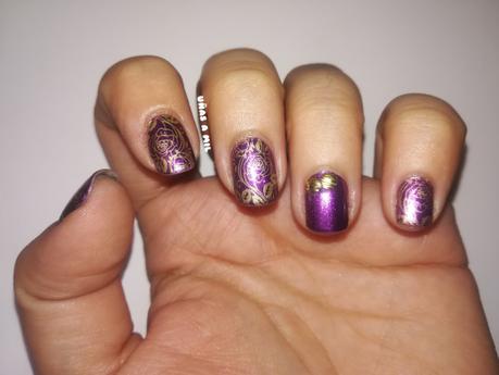 Diseño de uñas en morado y dorado con tachuelas