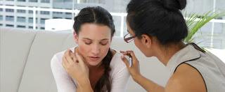 Mujer recibiendo ayuda para superar la pérdida de un ser querido. Ambas visten de blanco y la profesional tiene su mano puesta en el hombro de la paciente.