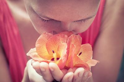 Chica oliendo el aroma de flores