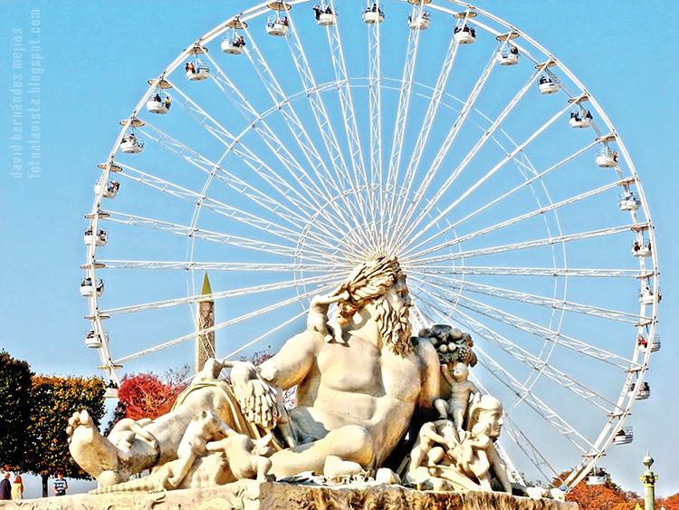 Imagen de escultura al aire libre de estilo greco-latino con la noria y el puntiagudo obelisco detrás, ubicados en los Campos Elíseos de París (Francia)
