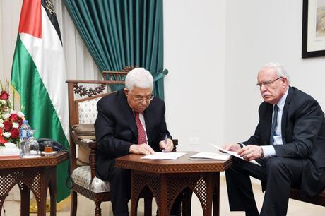 Mahmud Abás firmando en presencia del Ministro de Asuntos Exteriores palestino Riyadh al-Maliki aprobando la adhesión de la Autoridad Palestina a otros siete convenios internacionales (Wafa, 7 de junio de 2018)
