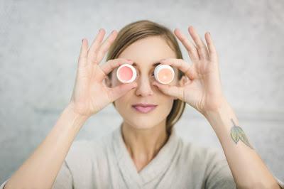 Mujer con tarros de maquillaje sobre los ojos