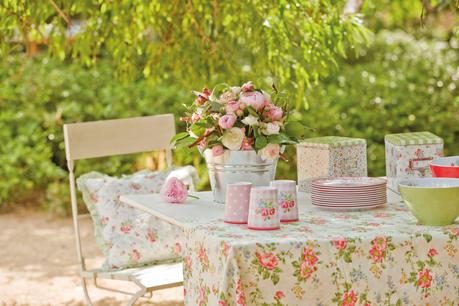Mesa de comedor en el jardín con silla de metal, mantel de flores y detalles románticos_ 228189