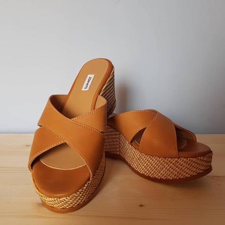 Un bolso de mimbre, un pintalabios, unas gafas de sol y unos zapatos Un bolso de mimbre, un pintalabios, unas gafas de sol y unos zapatos