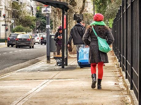 Joven de espaldas caminando con gorro rojo y tapado.