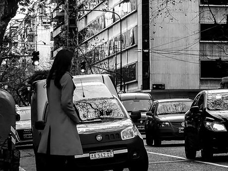 BYN.Una joven con tapado esperando cruzar la calle.