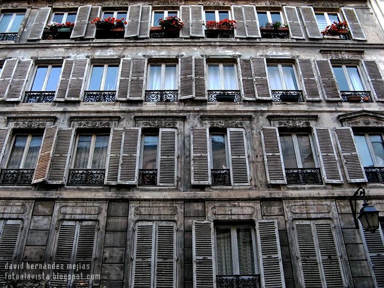 Balconada de una casa de París con contraventanas mayoritariamente abiertas, recordando el anuncio del perfume Égoïste
