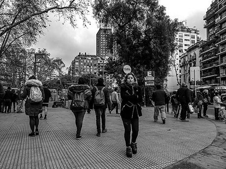 BYN.Joven caminando con muestras de frío entre la gente.