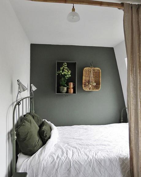 dormitorio con una pared pintada y el cabezal de hierro en verde