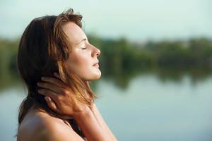 Woman stands with hands on neck at lakeside in France