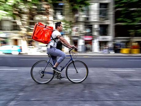 Joven delivery en bicicleta por la ciudad