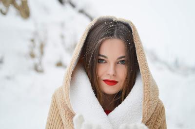 Mujer joven con los labios pintados de rojo intenso en un paisaje invernal