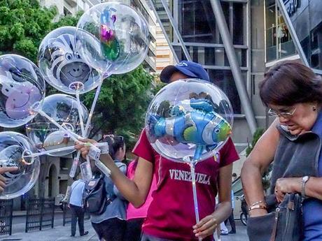 Vendedora ambulante de globos transparente con muñecos en el interior.