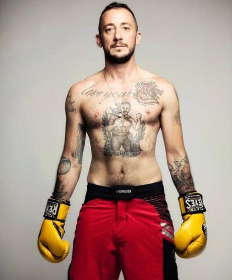 Thomas McBee posando con guantes y pantalón de boxeo, sin camiseta, mostrando tatuajes.