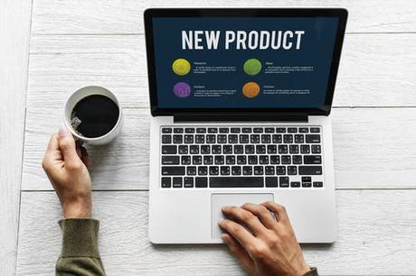 Person Holding Mug Beside Turned-on Macbook