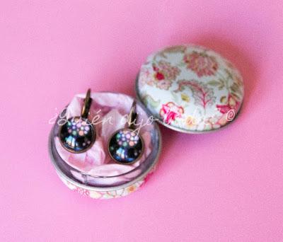 Caja metálica con estampado floral con pendientes sobre papel de seda Caja metálica con estampado floral con pendientes sobre papel de seda