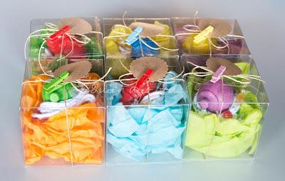 Peonzas de madera empaquetadas en cajas de acetato sobre papel de seda con detalle de etiquetas y pinzas Peonzas de madera empaquetadas en cajas de acetato sobre papel de seda con detalle de etiquetas y pinzas