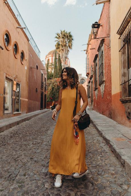 Sara of Collage Vintage wearing a long mustard dress and embroidered sneakers