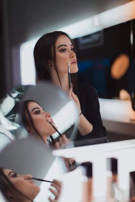 Mujer aplicándose maquillaje con una brocha delante de un espejo