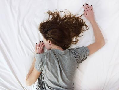 Mujer durmiendo boca a bajo sobre sábanas blancas