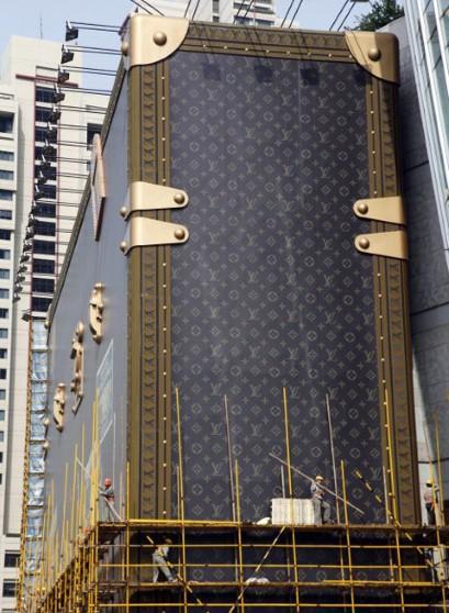 Workers dismantle a giant advertisement display modeling a Louis Vuitton suitcase outside a Louis Vuitton branch on Thursday, May 19, in Shanghai, China
