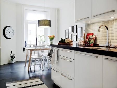 suelo de losas de piedra italiana sofá chaiselong salón y cocina en dos niveles piso sueco piso en dos niveles paredes redondeadas muebles de cocina bajos estilo nórdico estilo escandinavo escaleras de cristal diseño de interiores decoración sueca decoración de interiores cuadro con zapatos colcha rosa cocina moderna cocina blanca 