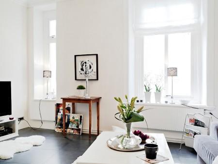 suelo de losas de piedra italiana sofá chaiselong salón y cocina en dos niveles piso sueco piso en dos niveles paredes redondeadas muebles de cocina bajos estilo nórdico estilo escandinavo escaleras de cristal diseño de interiores decoración sueca decoración de interiores cuadro con zapatos colcha rosa cocina moderna cocina blanca 