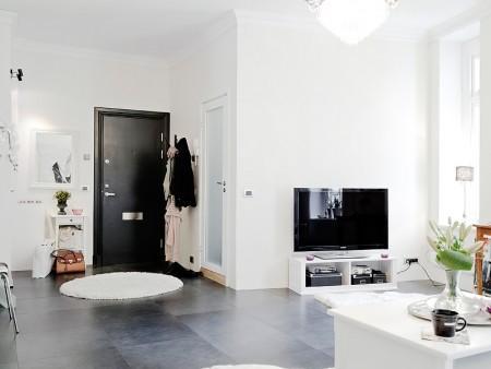 suelo de losas de piedra italiana sofá chaiselong salón y cocina en dos niveles piso sueco piso en dos niveles paredes redondeadas muebles de cocina bajos estilo nórdico estilo escandinavo escaleras de cristal diseño de interiores decoración sueca decoración de interiores cuadro con zapatos colcha rosa cocina moderna cocina blanca 