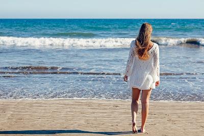 Chica paseando por la playa con un vestido