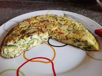 Tortilla empezada de calabacín con cebolla en plato.