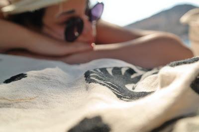 Chica tumbada en la playa tomando el sol con sombrero y gafas
