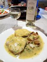 Merluza con almejas en salsa verde acompañada de vino blanco.
