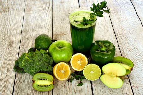 Imagen que muestra batido verde de frutas y vegetales; alrededor vegetales y verduras enteros