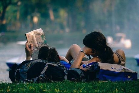 Pareja joven acostada en el césped con un mapa.