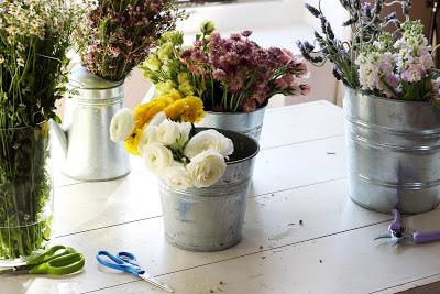 Flores en cubos de zinc sobre una mesa de trabajo 
